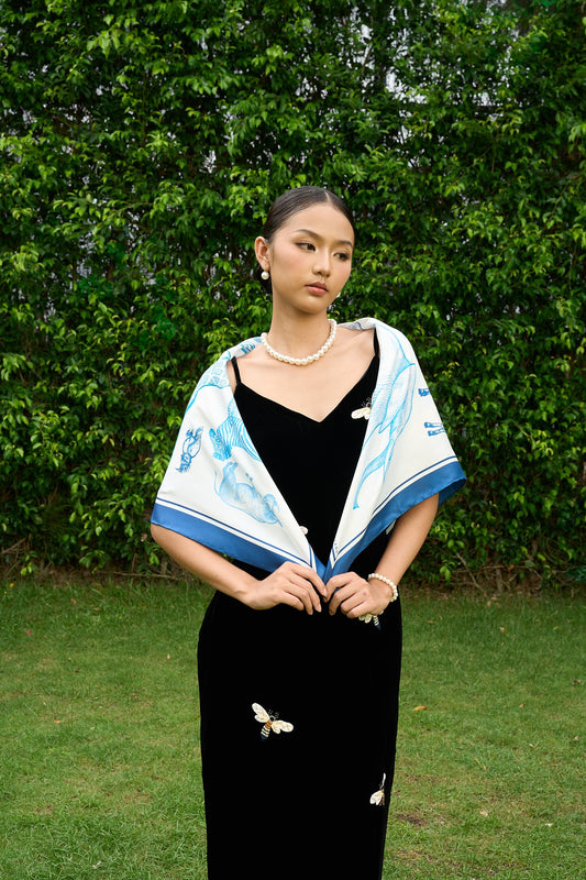 Model wearing the cornflower blue and ivory animal print silk scarf draped over the shoulders with a black dress