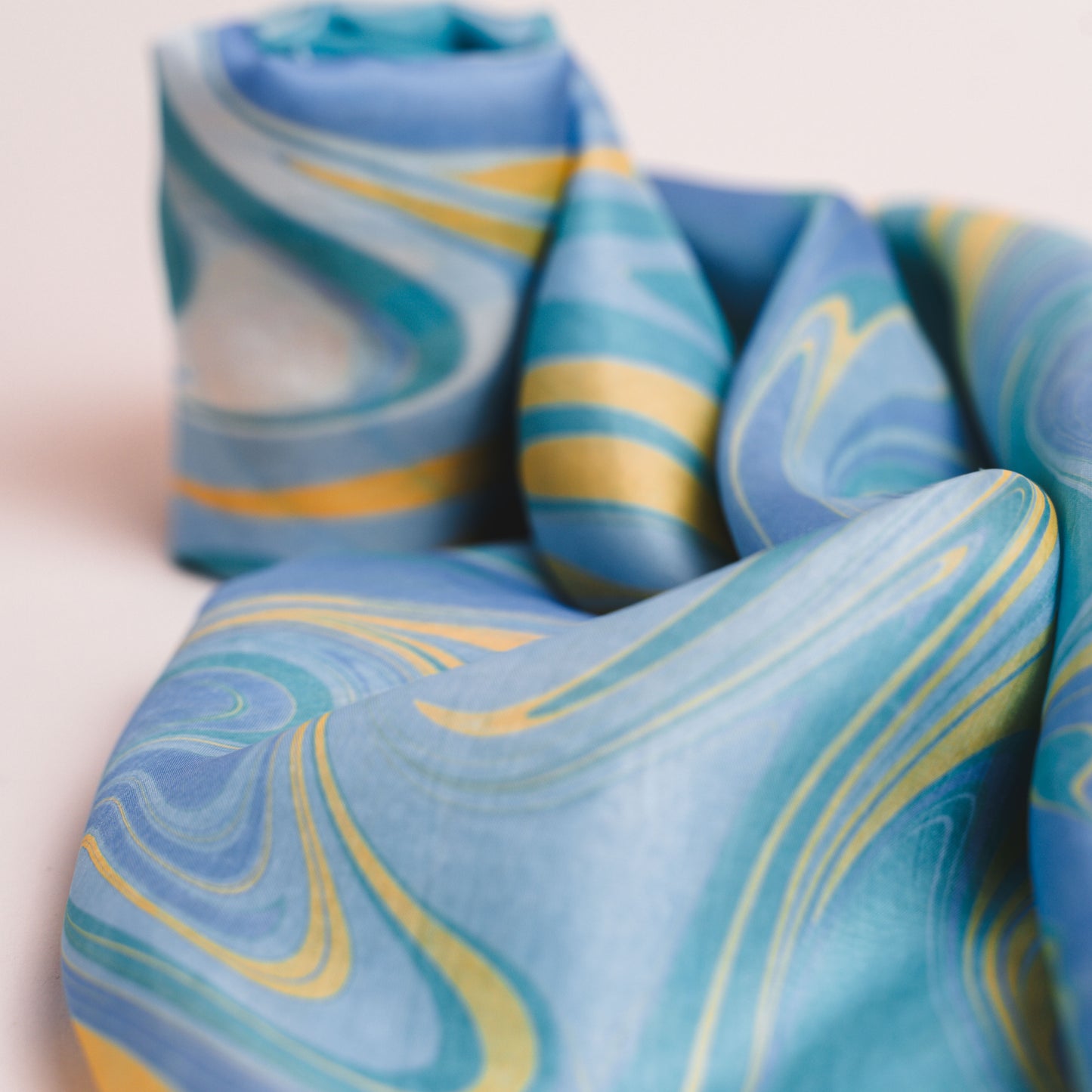 Marbled blue mulberry silk scarf styled loosely around the neck, a lightweight wrap