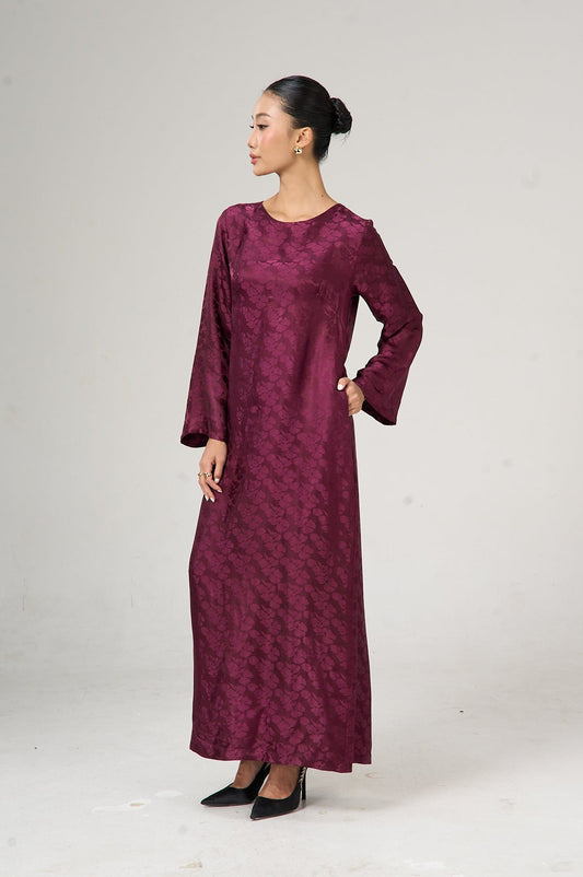 Woman wearing a burgundy long-sleeve dress on a white background