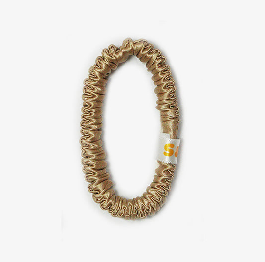 Skinny beige silk scrunchies worn in the hair