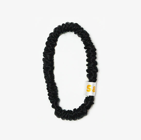 Skinny black silk scrunchies worn in the hair