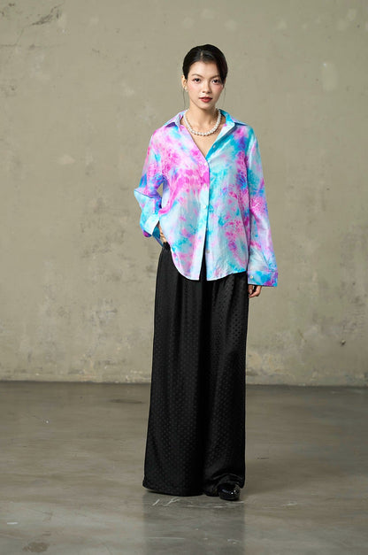 Model in Lagoon Bloom hand tie-dyed pink and turquoise silk shirt with black wide-leg trousers, full length