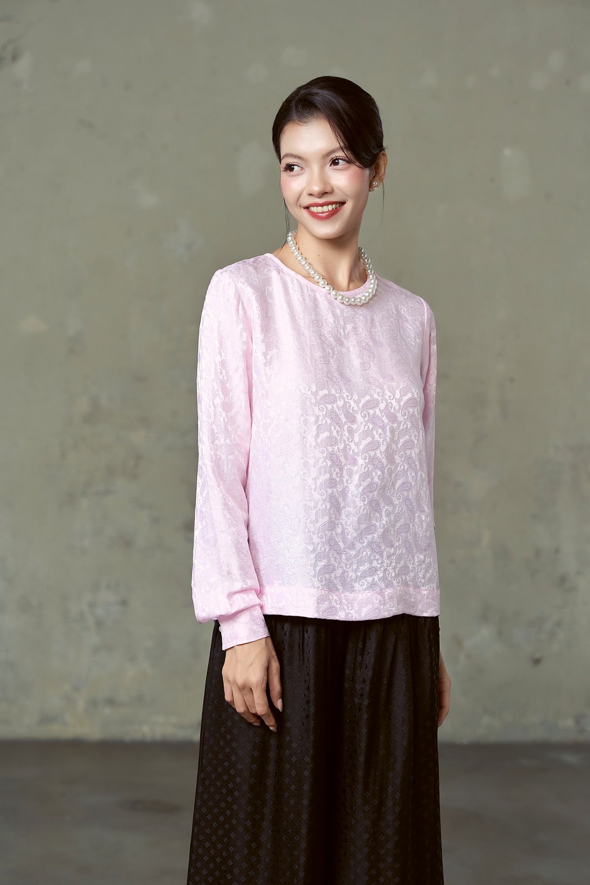 Model in blush pink paisley silk jacquard blouse with long sleeves and pearls, Rosalind Blush Paisley