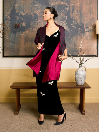 Plum and fuchsia reversible silk shawl worn open over a black velvet dress, showing the plum face outside and the fuchsia face inside