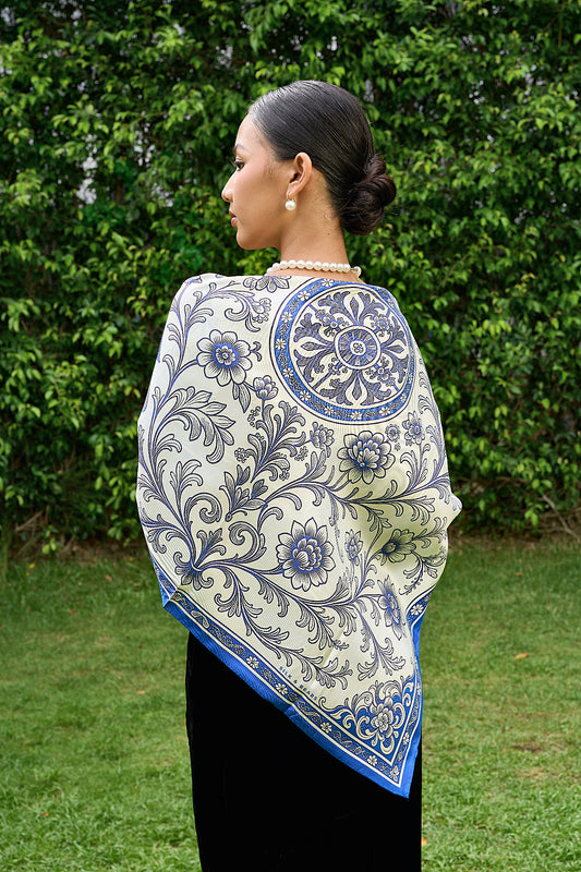 Model wearing the blue chinoiserie birds silk scarf as a shoulder wrap over a black velvet dress