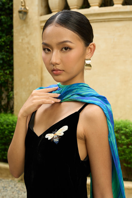 Close-up of the green and blue brushstroke silk scarf draped around the neck