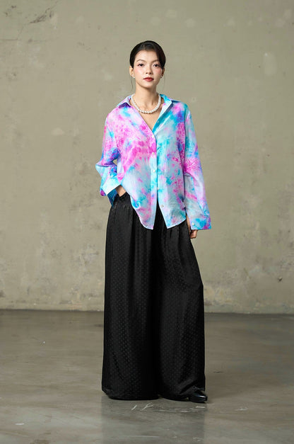 Relaxed oversized tie-dye silk shirt worn loose over black silk wide-leg trousers