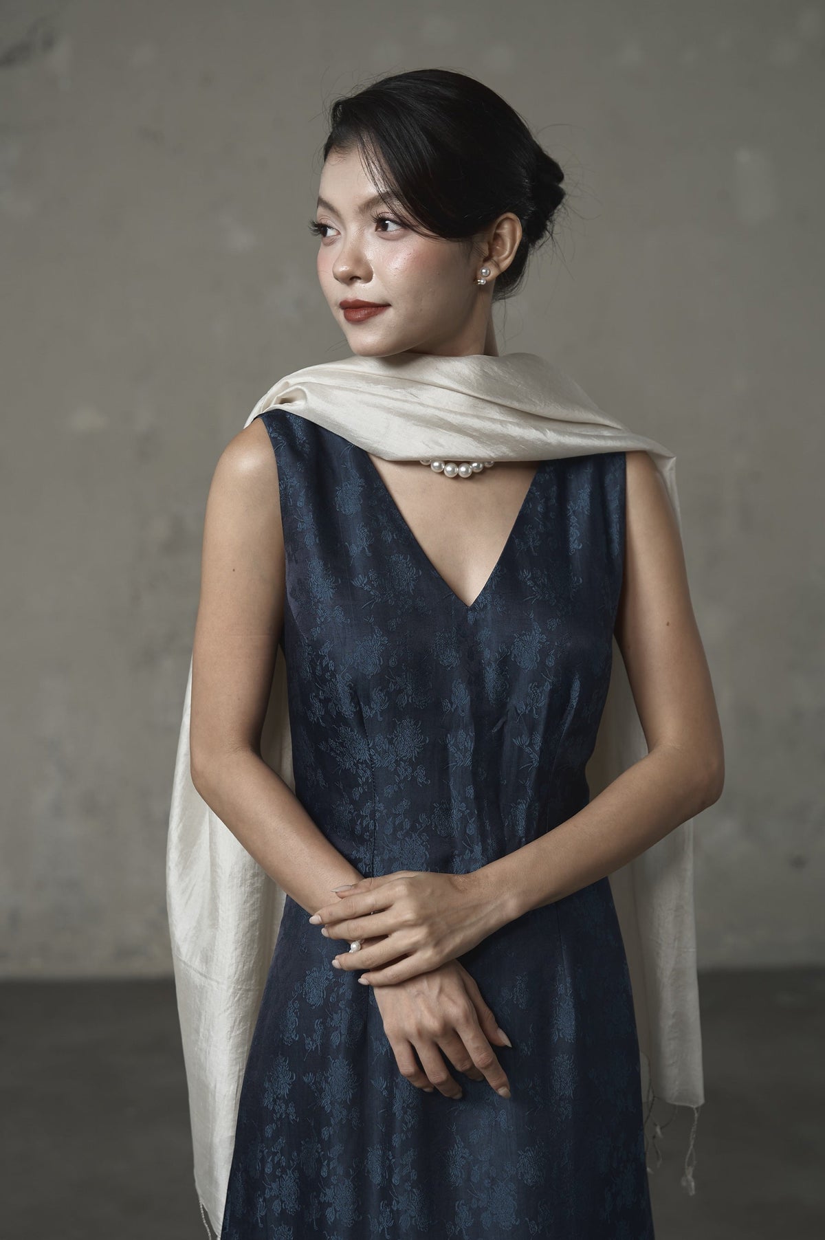 Model wearing the oyster silk scarf draped at the neck over a navy jacquard dress