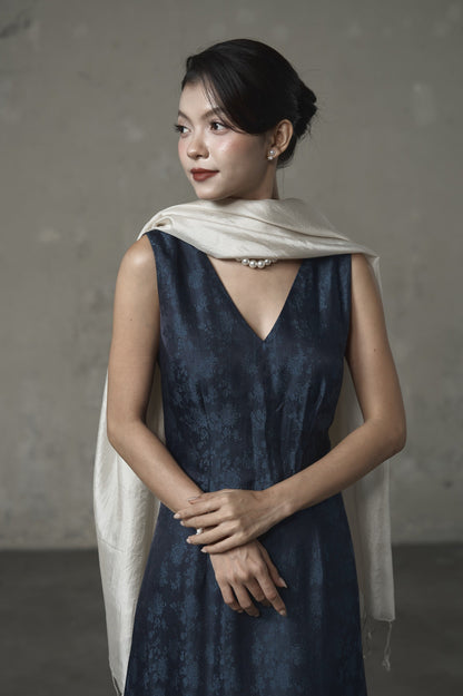 Model wearing the oyster silk scarf draped at the neck over a navy jacquard dress