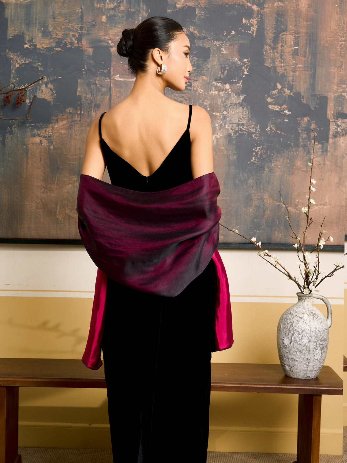 Back view of the plum reversible silk shawl draped across the shoulders over a backless black dress