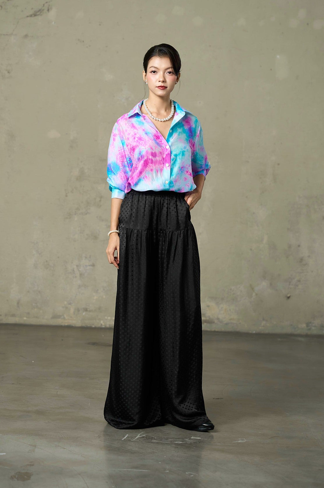 Pink and blue tie-dye silk shirt half-tucked into black jacquard trousers, front view