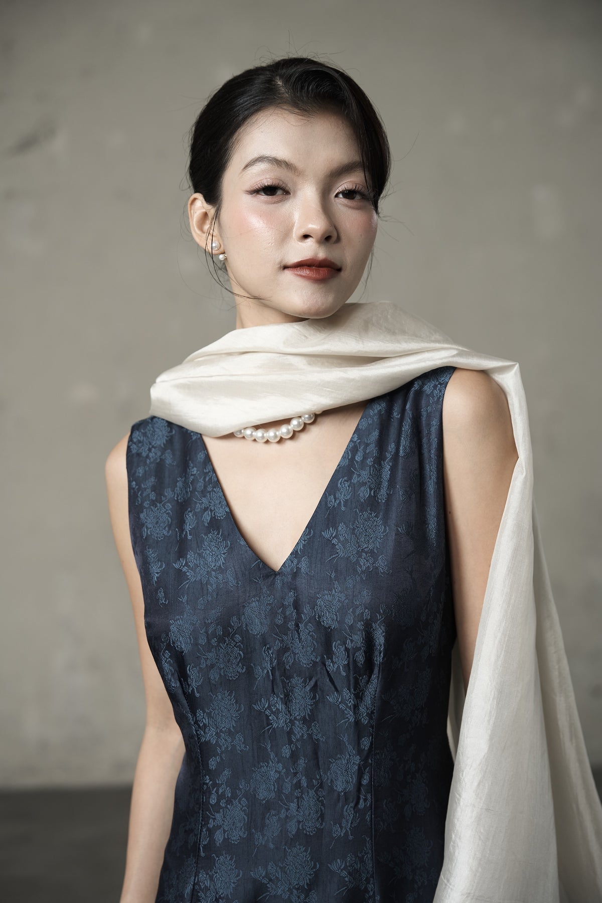 Close view of the oyster silk scarf wrapped at the neck, showing the weave and its lustre