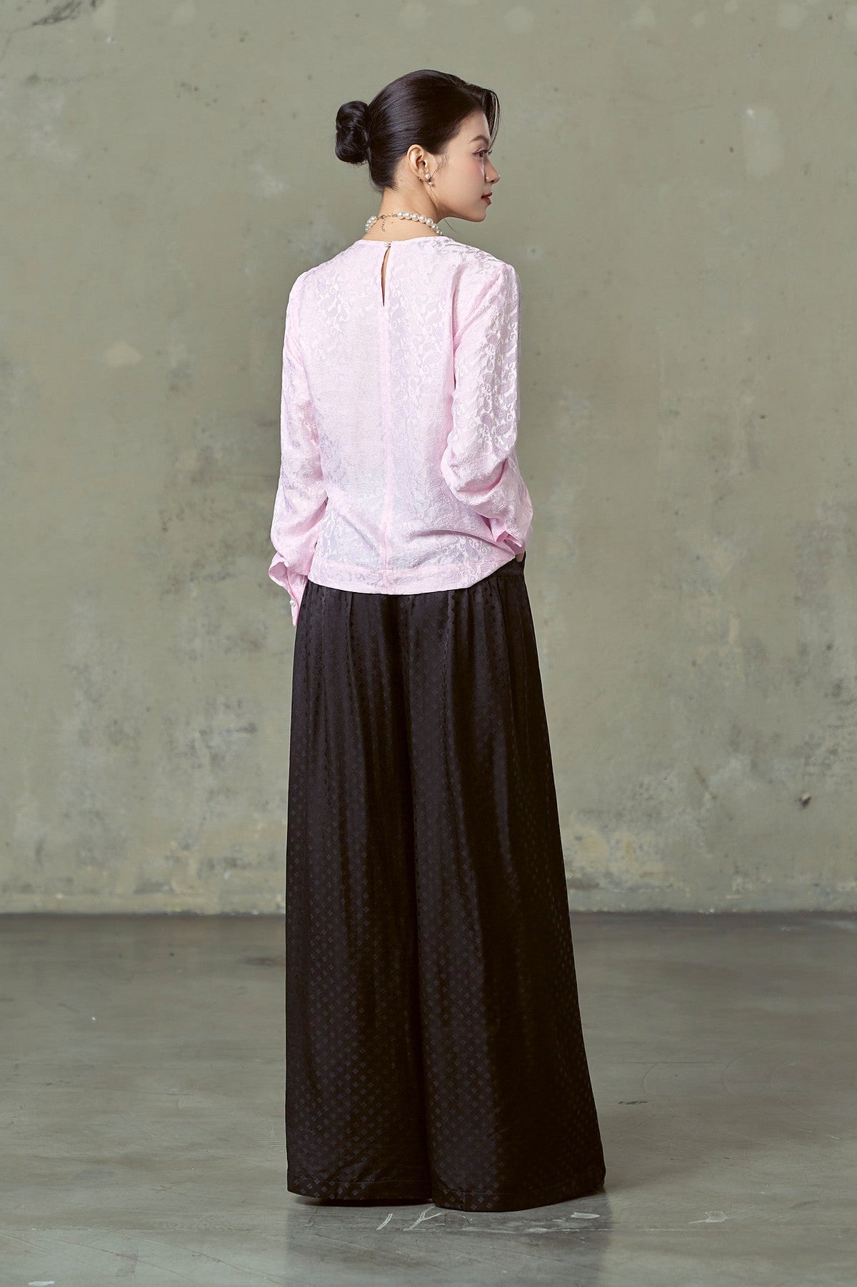 Back view of pink paisley silk blouse with keyhole button neck, styled with black silk trousers