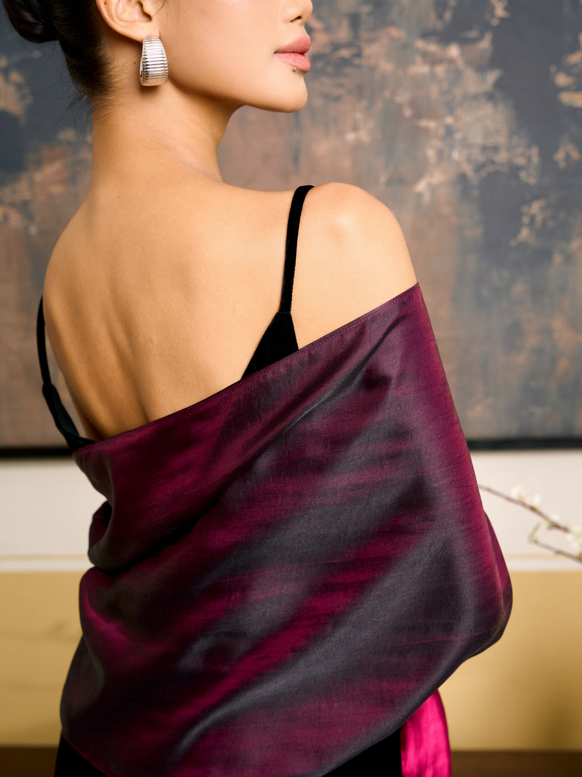 Close-up of the iridescent plum face of the reversible silk shawl at the shoulder, with fuchsia glinting through