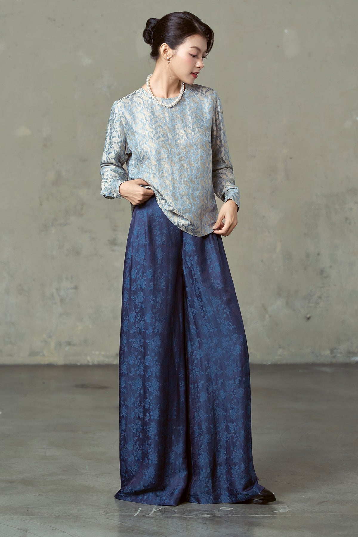 Navy silk wide-leg trousers moving at the hem, worn with blue paisley blouse