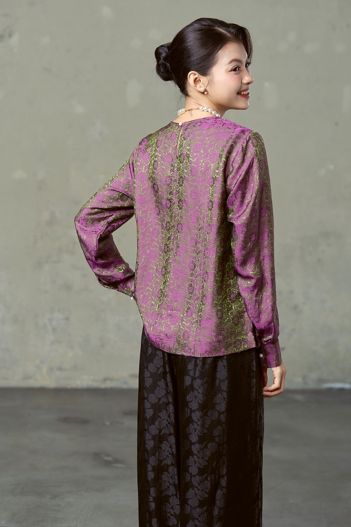 Back view of magenta olive floral silk blouse with black jacquard wide-leg trousers