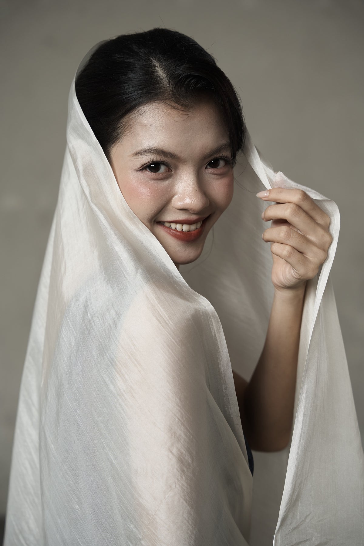 Oyster hand-dyed silk held to the light, showing the semi-sheer weave and pearl lustre