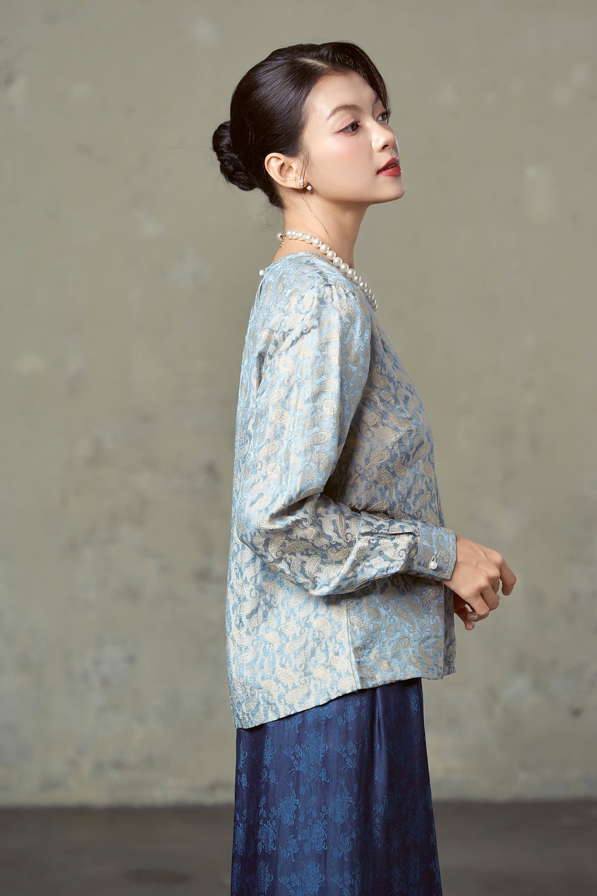 Side view of porcelain blue paisley silk jacquard blouse with buttoned cuff