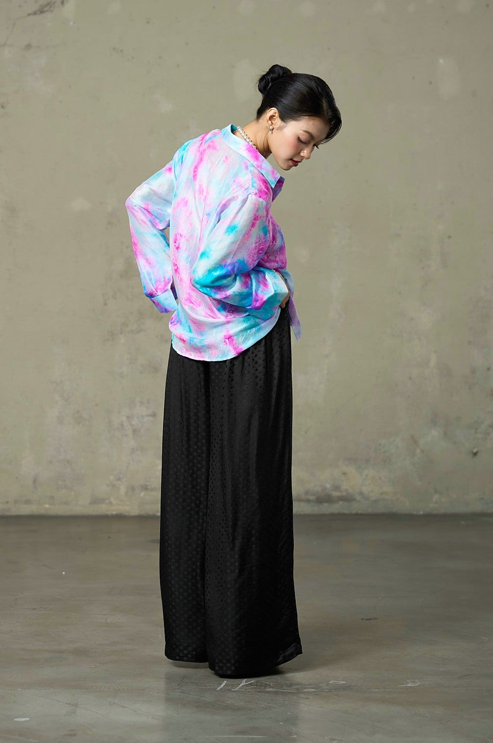 Model turning in hand-dyed pink and turquoise silk shirt, showing the light habotai drape