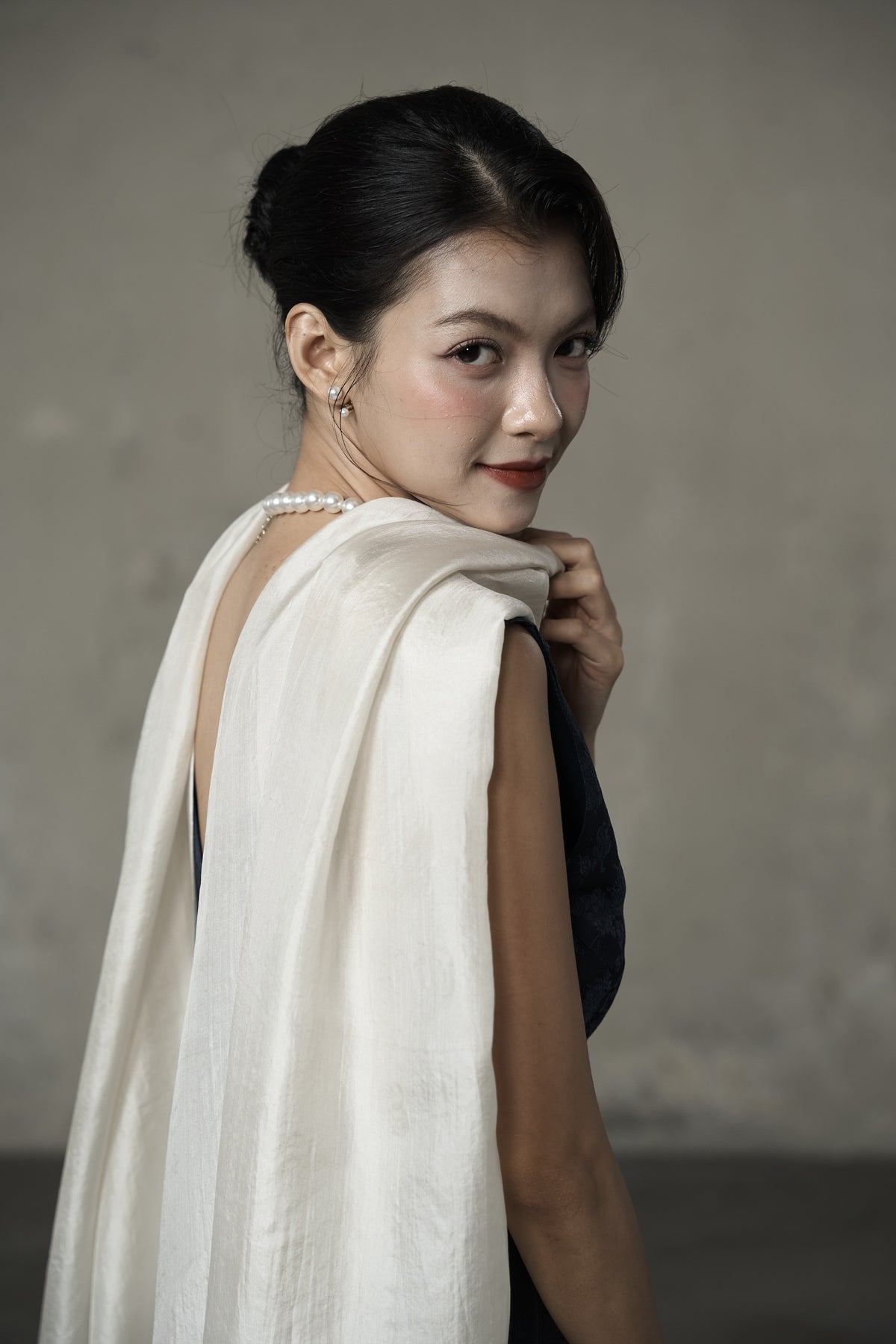 Oyster silk scarf folded over the shoulder as a wedding guest wrap