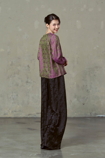 Model turning to look back in magenta and olive silk jacquard blouse, showing the shot colour
