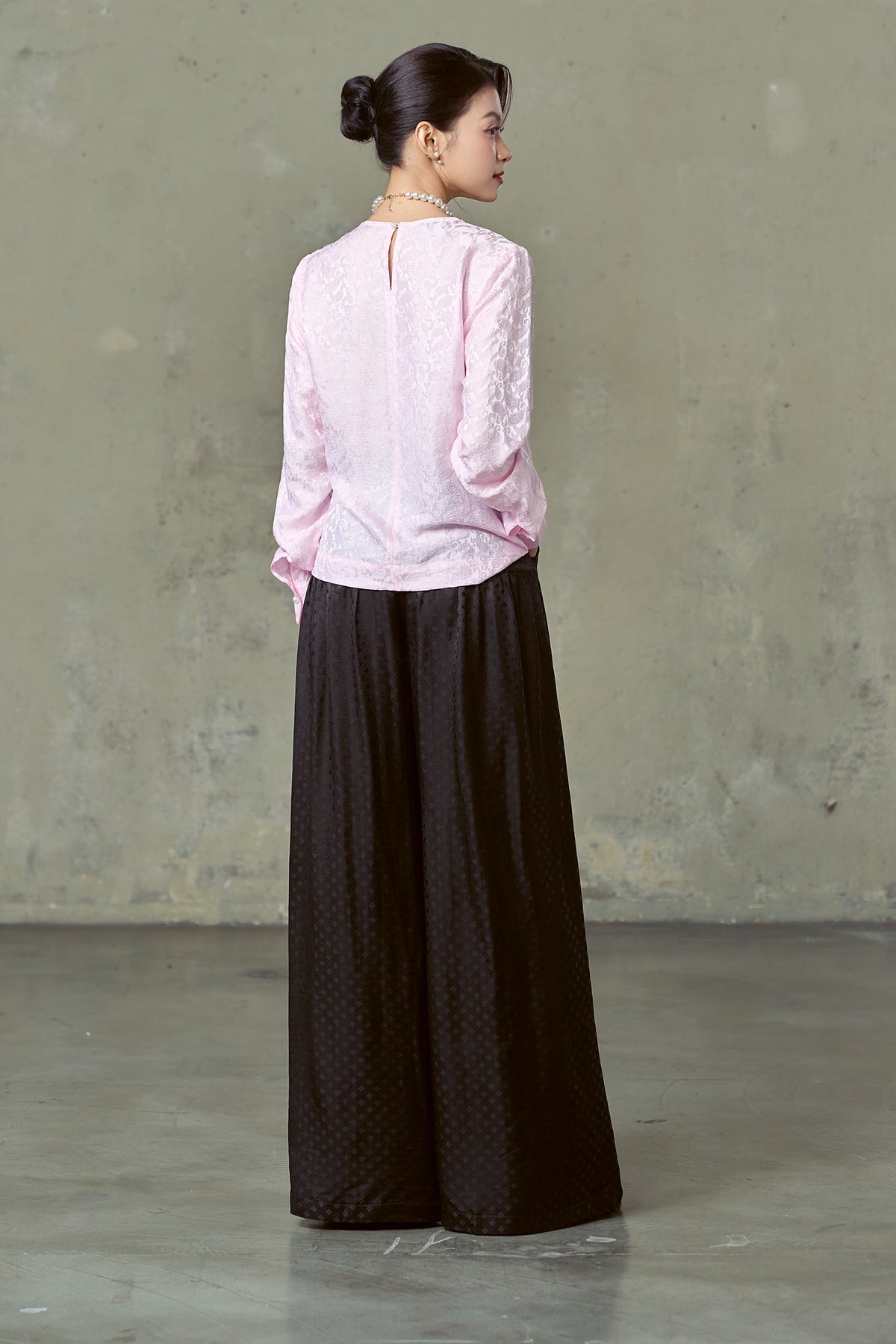 Back view of floor-length black diamond-dot silk wide-leg trousers