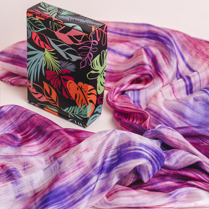 Purple and pink brushstroke hand-dyed silk scarf shown against an artistic backdrop