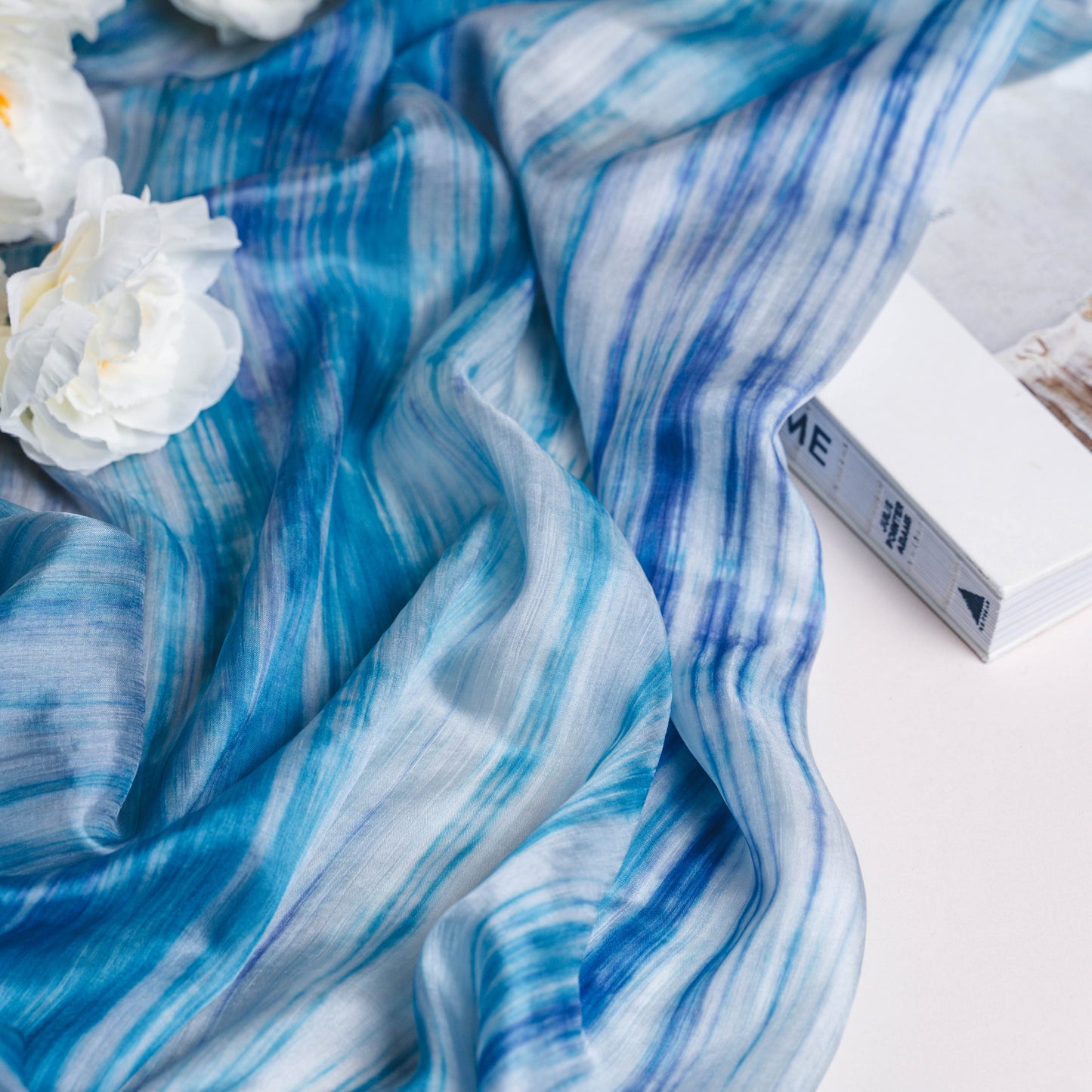 Sky blue brushstroke mulberry silk scarf styled loosely around the neck