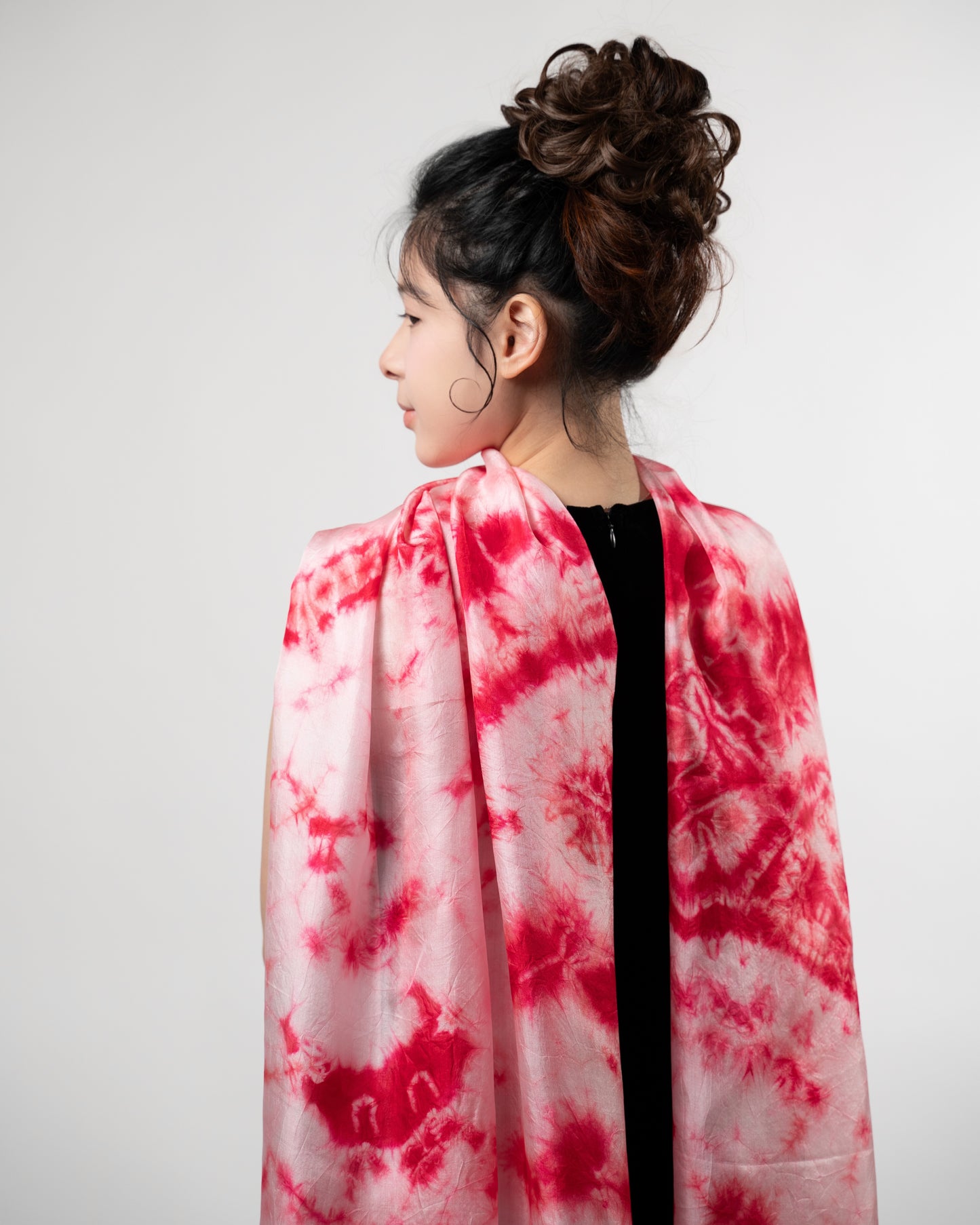 Crimson red shibori silk scarf held open to show the full pattern