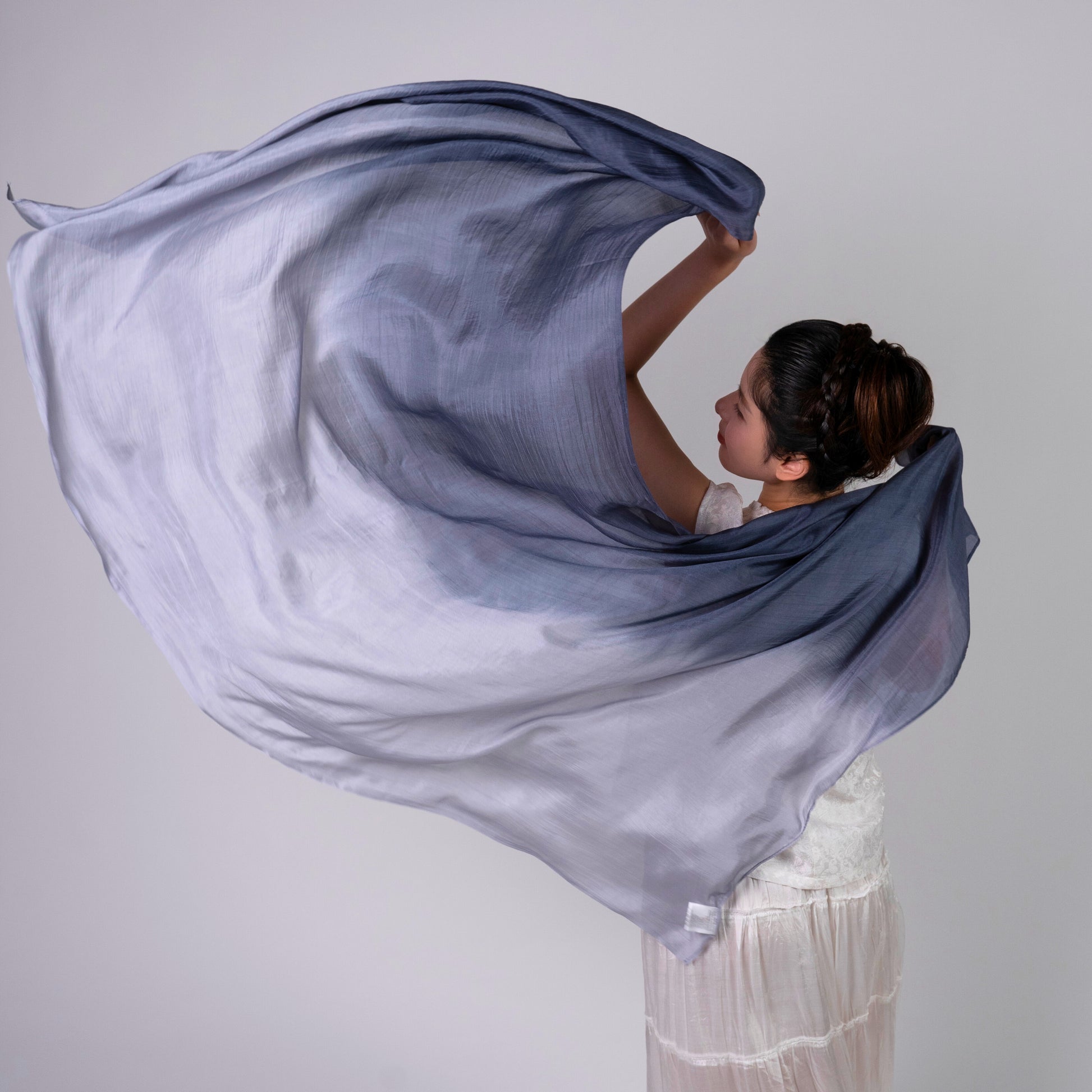Grey and white ombre silk scarf styled softly over the shoulders, a lightweight wrap