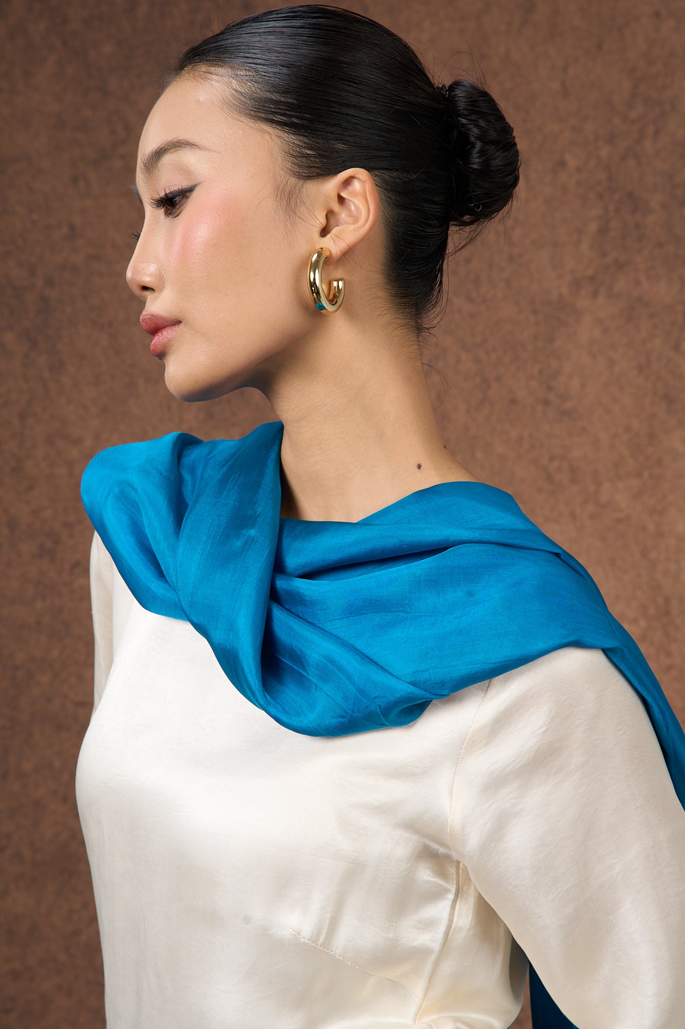 Teal blue mulberry silk scarf styled loosely around the neck, a lightweight wrap