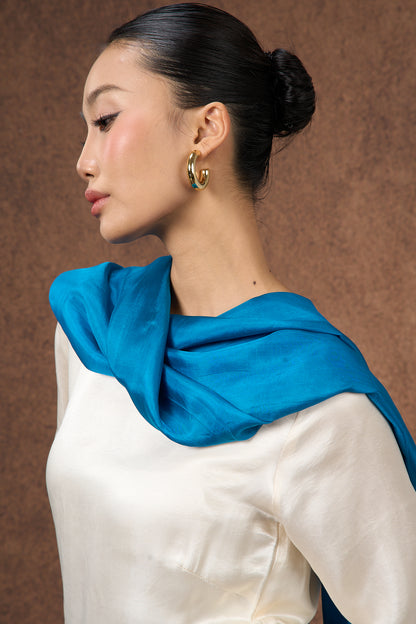Teal blue mulberry silk scarf styled loosely around the neck, a lightweight wrap