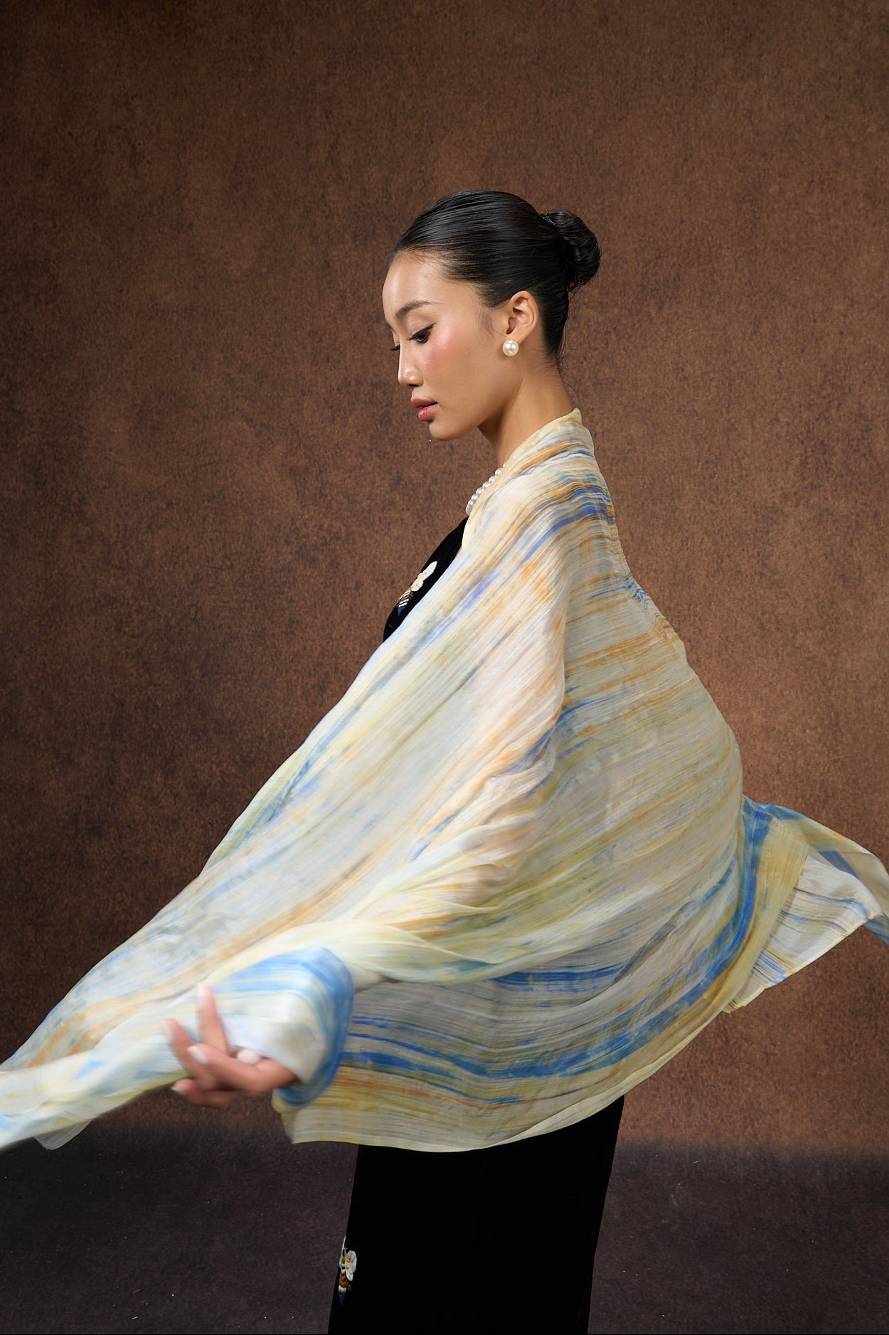 Back view of a model wearing the butter yellow and blue brushstroke silk shawl