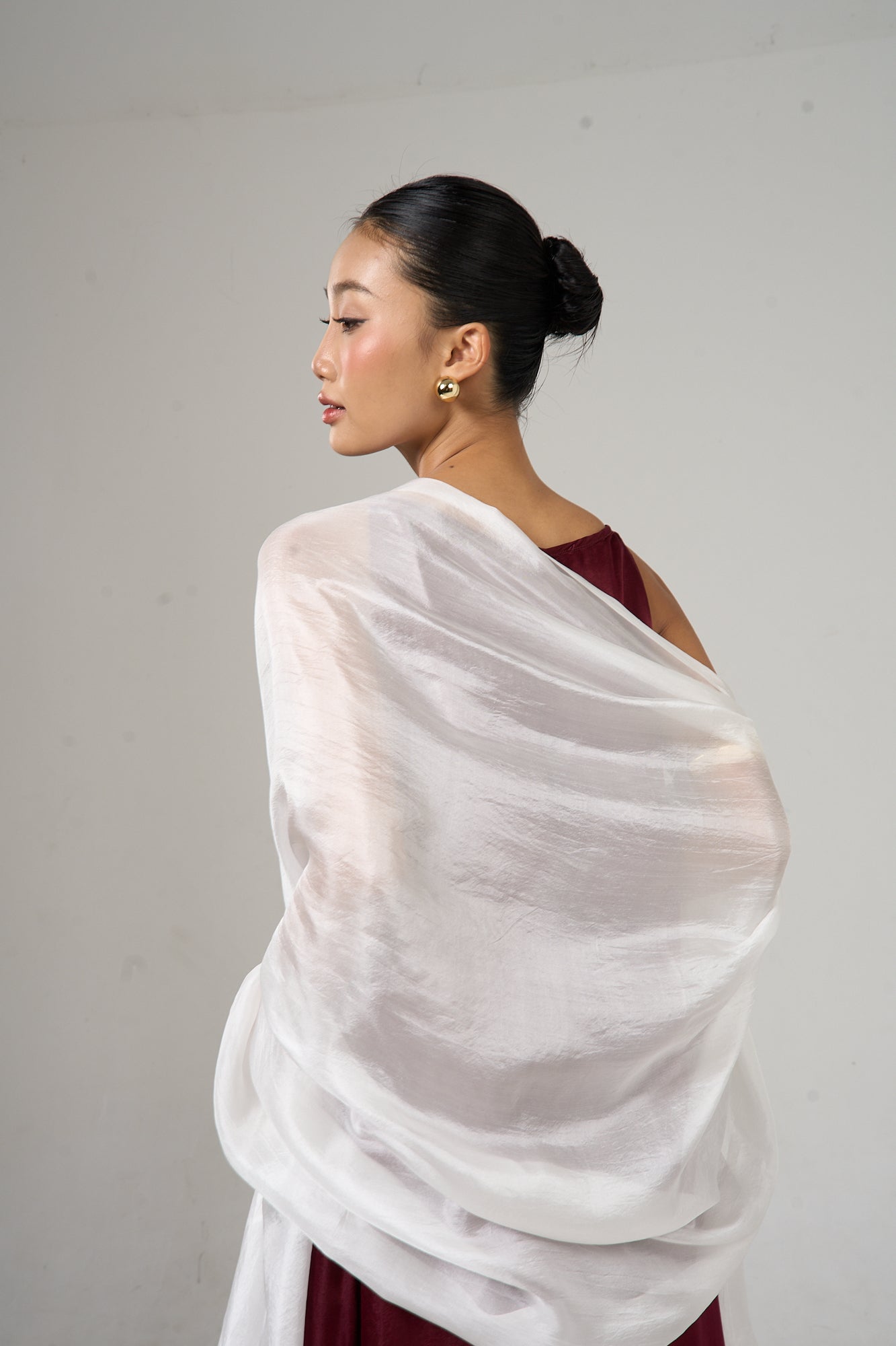Pearl white mulberry silk scarf styled loosely around the neck, a lightweight wrap