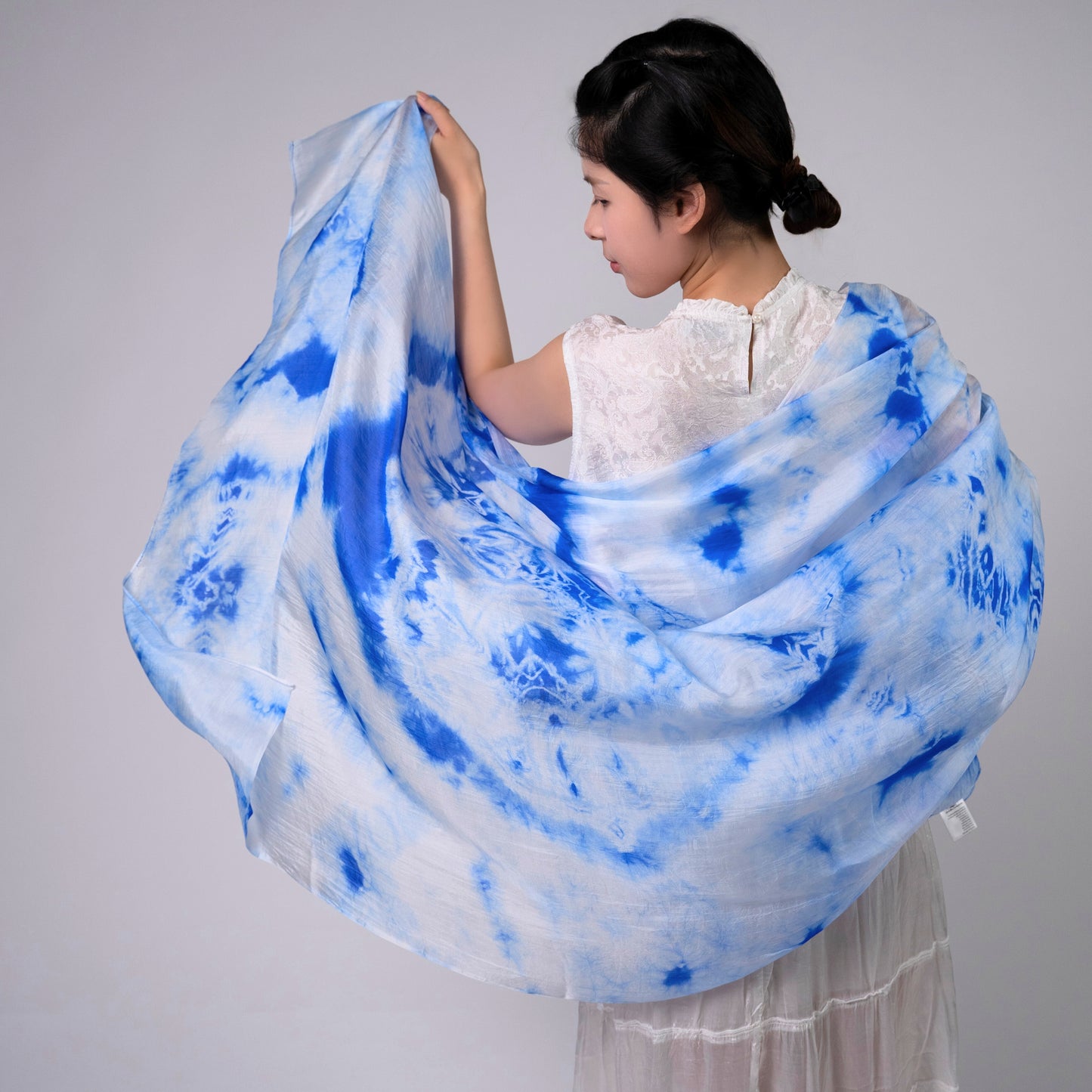 Sky blue shibori silk scarf held open to show the full pattern