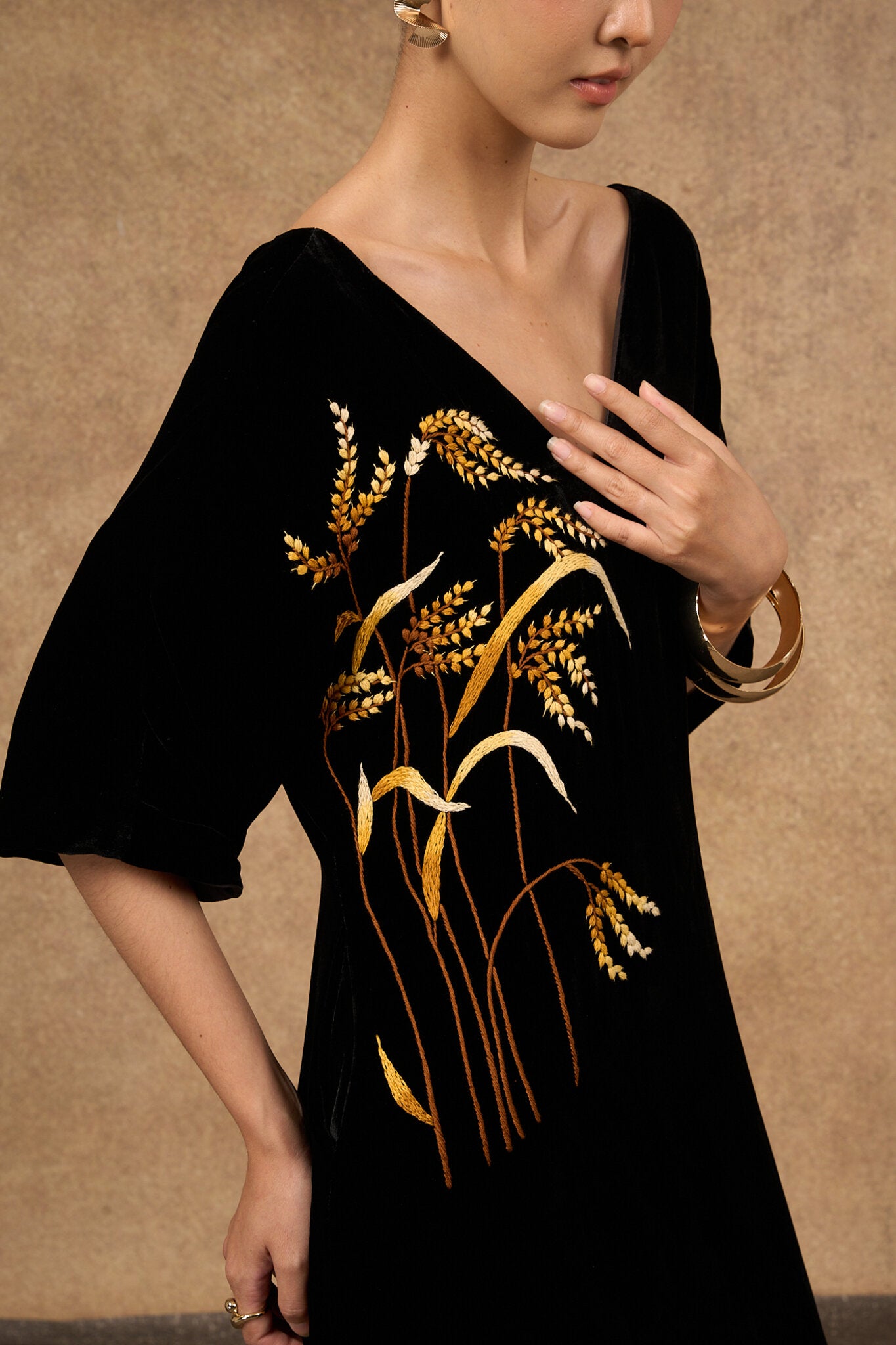 Model wearing the hand-embroidered black and gold silk velvet kimono-sleeve dress
