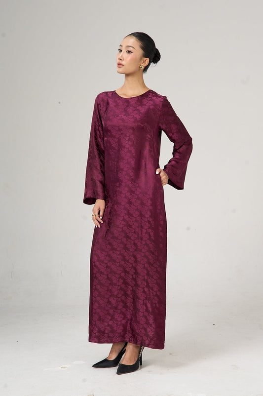 Woman wearing a long burgundy dress against a white background