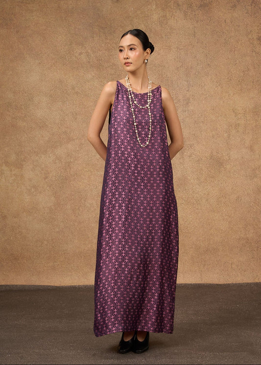 Woman wearing a long purple dress with a subtle pattern against a brown background