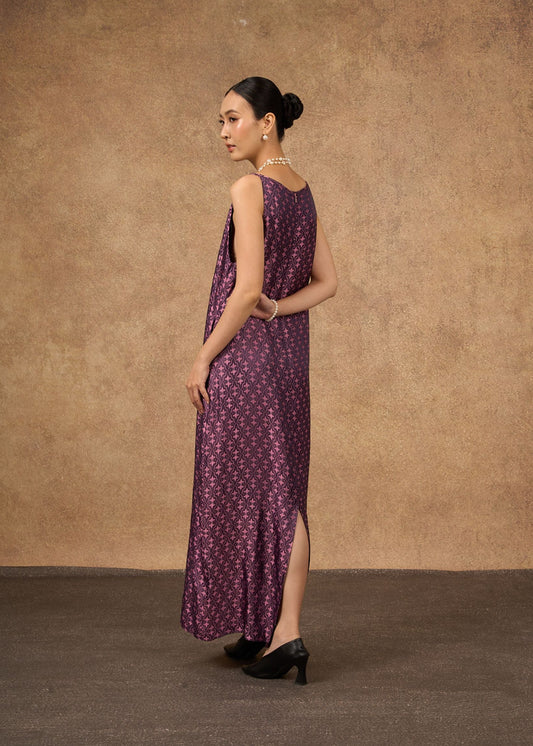 Woman wearing a long purple dress with a pattern against a brown background