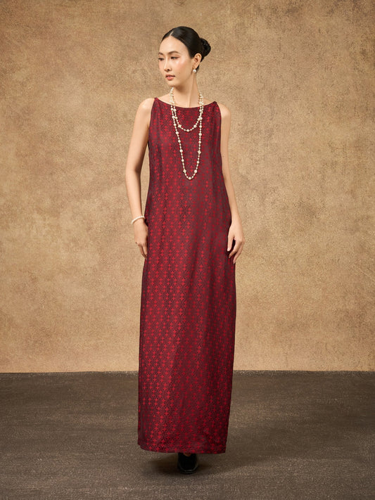 Woman wearing a long burgundy dress with a textured pattern against a brown background